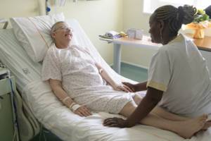 Personne âgée sur son lit d'hôpital avec aide-siognante